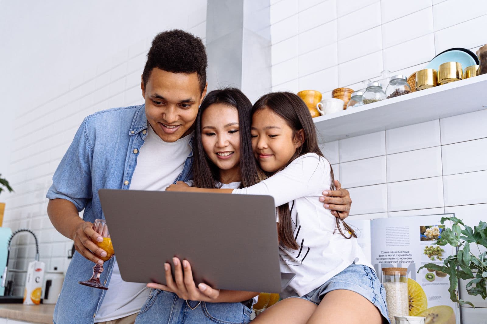 A family of three at their kitchen table, smiling as they read their child's plan in plain words on a laptop